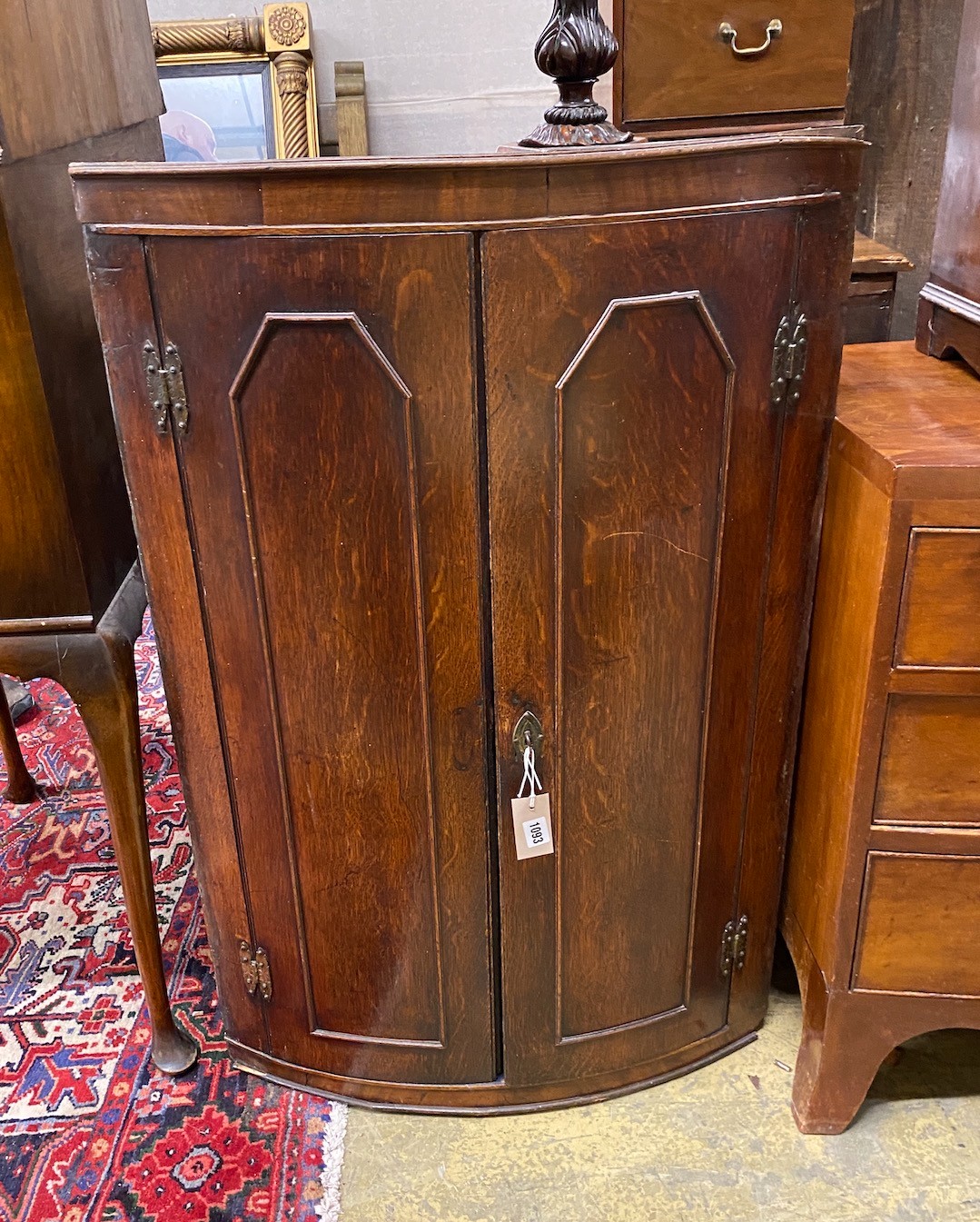 A George III oak bow front hanging corner cupboard, width 64cm, depth 40cm, height 100cm